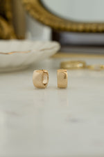 Gold chunky hoop earrings with a blurred background
