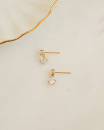Gold diamond stud earrings on plain background