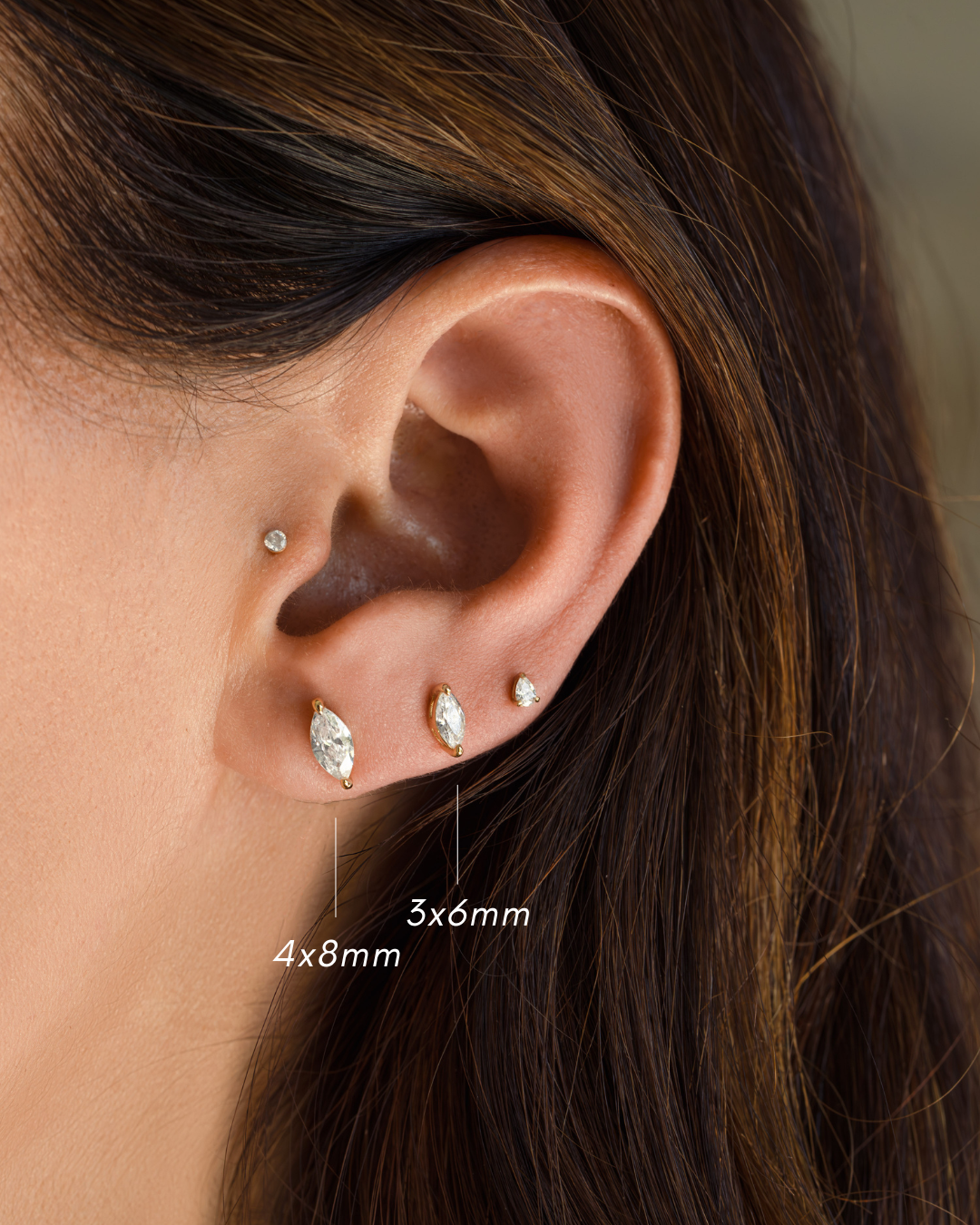 Model wearing bridal earrings, in the first hole a 4x8mm marquise stud earring, in the second hole, a 3x6mm small earring, and in the third a pear cut small stud earring