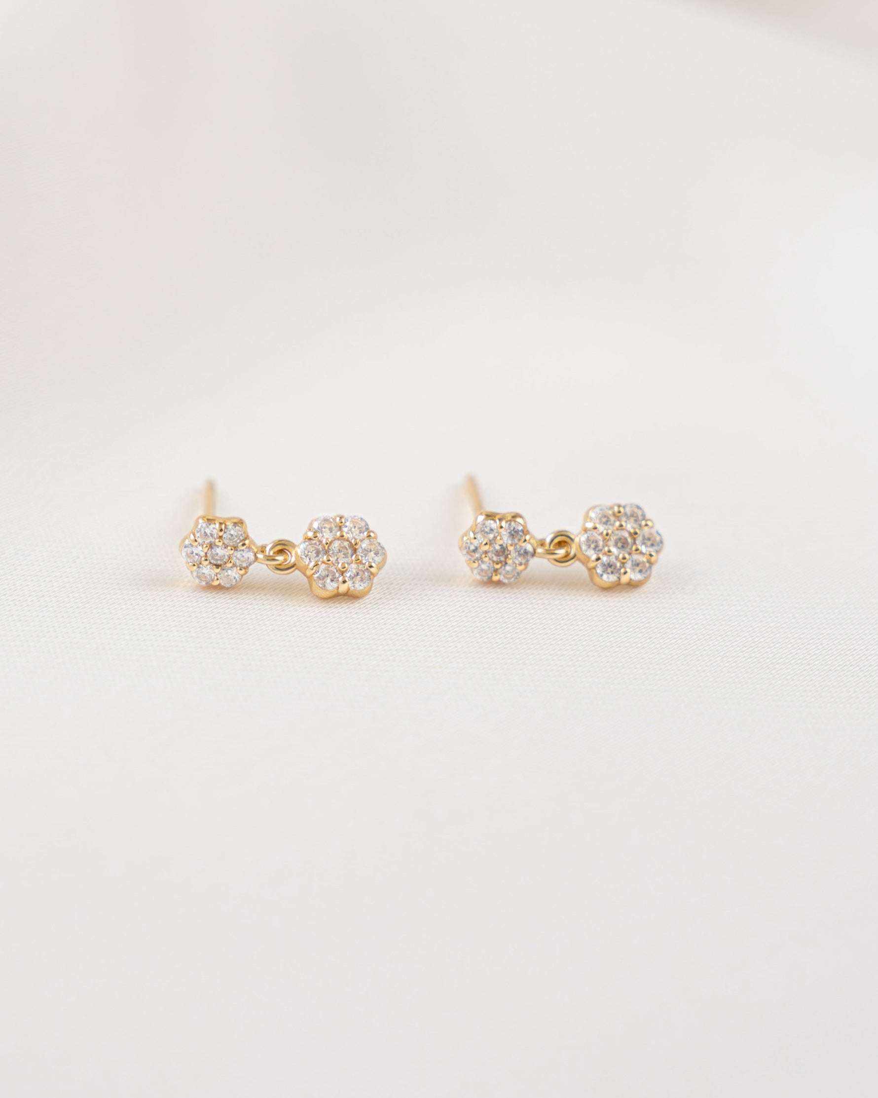 Pair of charm earrings on a light beige background