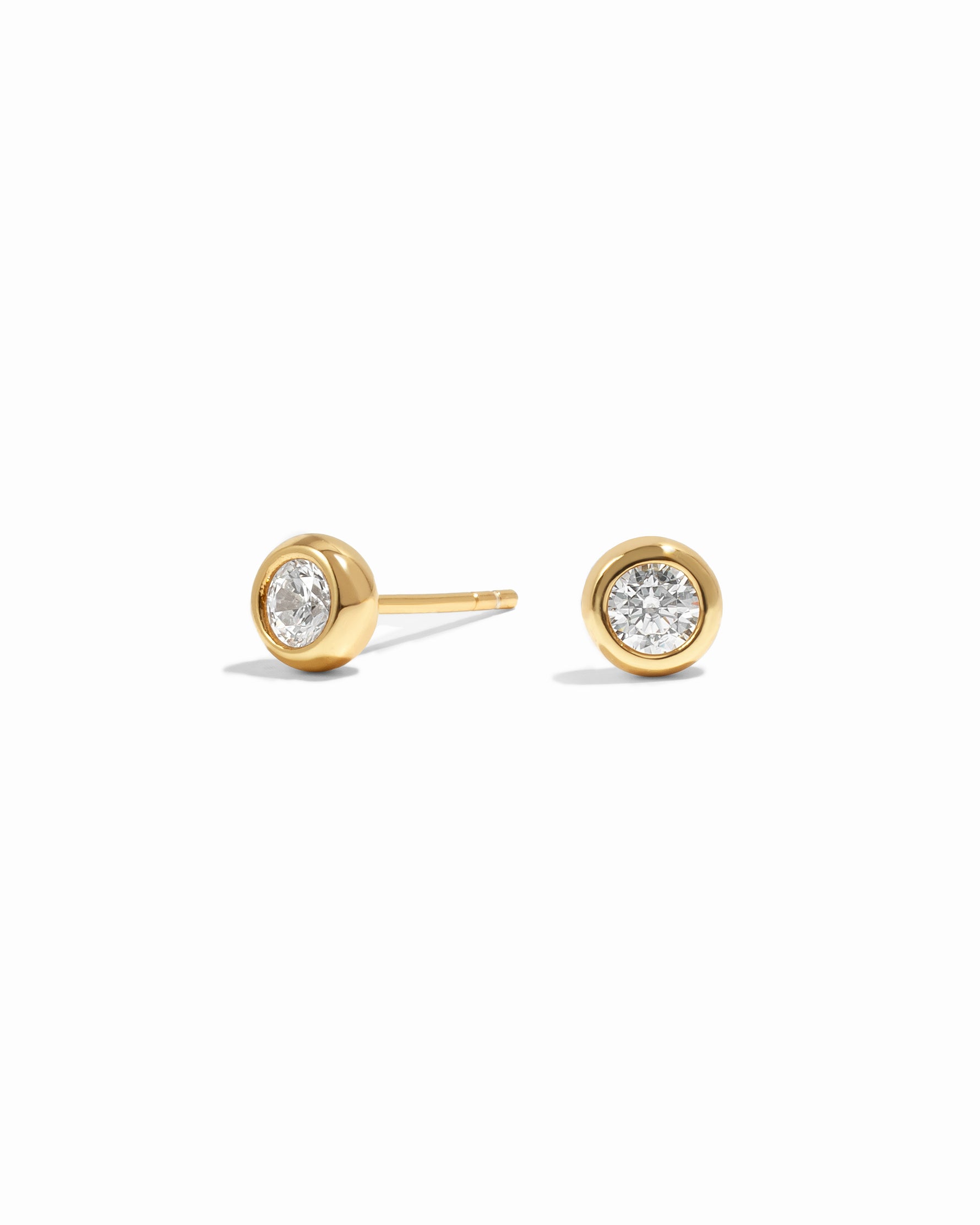 Gold stud earrings with cubic zirconia gemstones on a white background