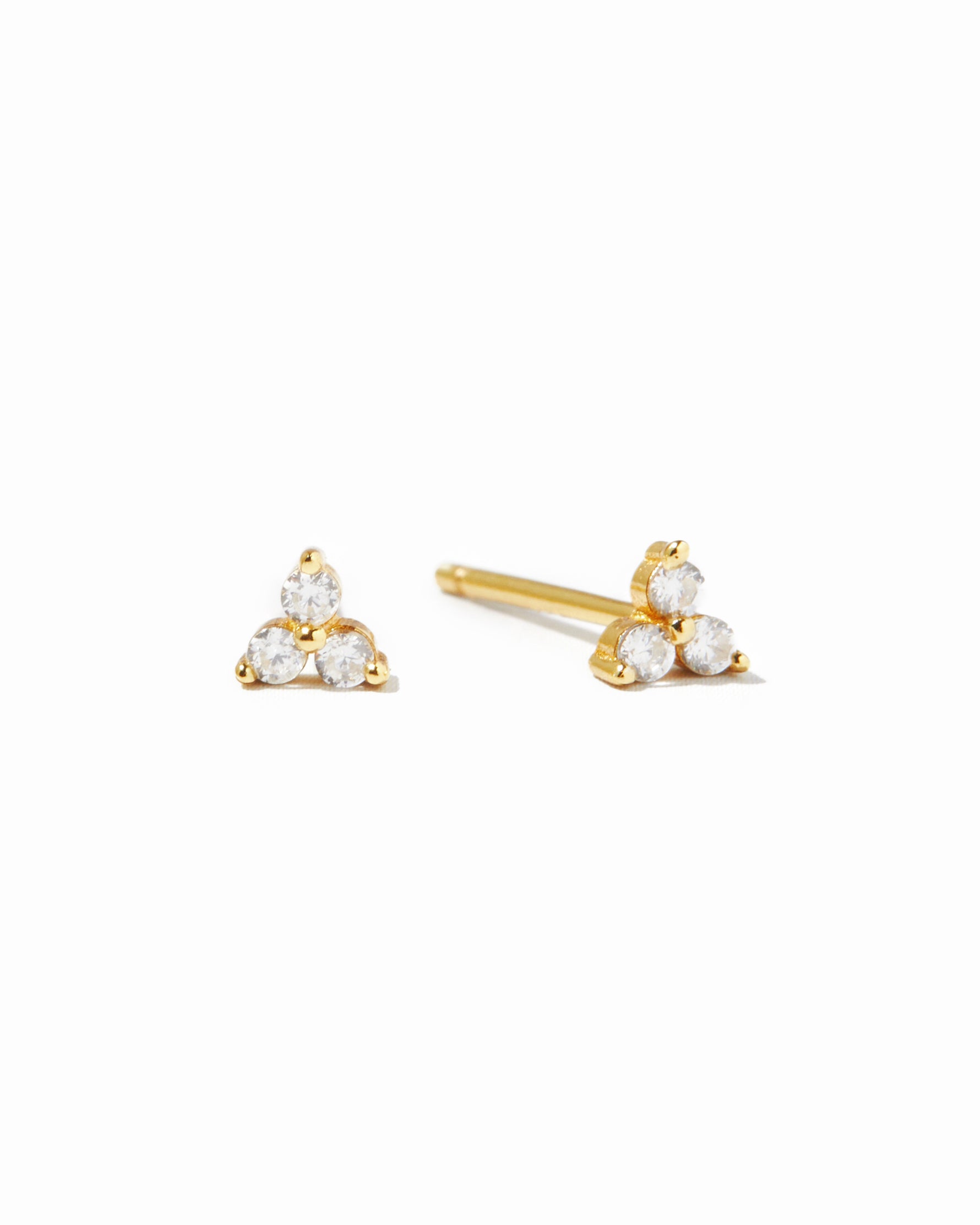 Gold triangle-shaped earrings with three white cz gemstones on a white background