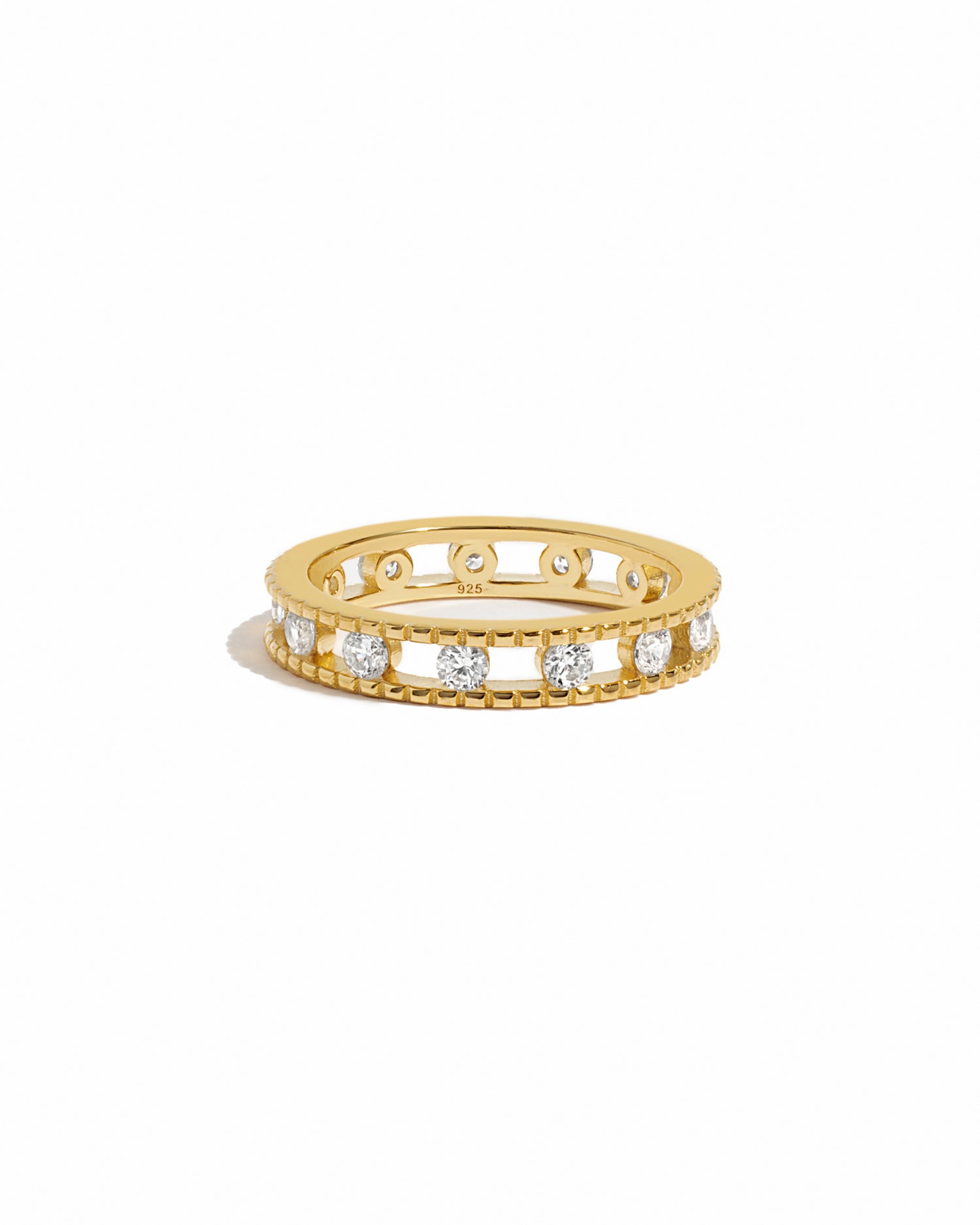 Gold ring with embedded cubic zirconia diamonds around a gold eternity band on a white background