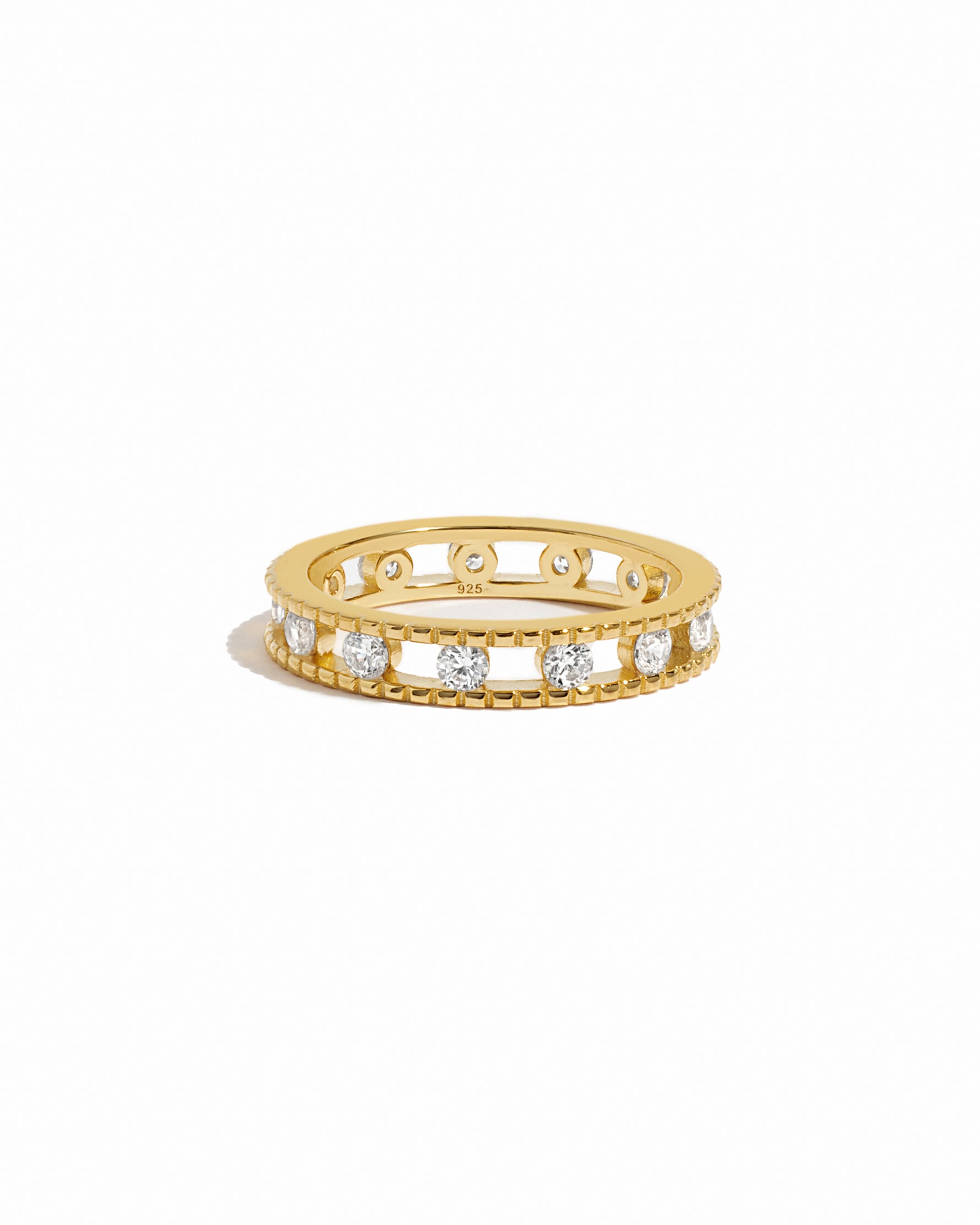 Gold ring with embedded cubic zirconia diamonds around a gold eternity band on a white background