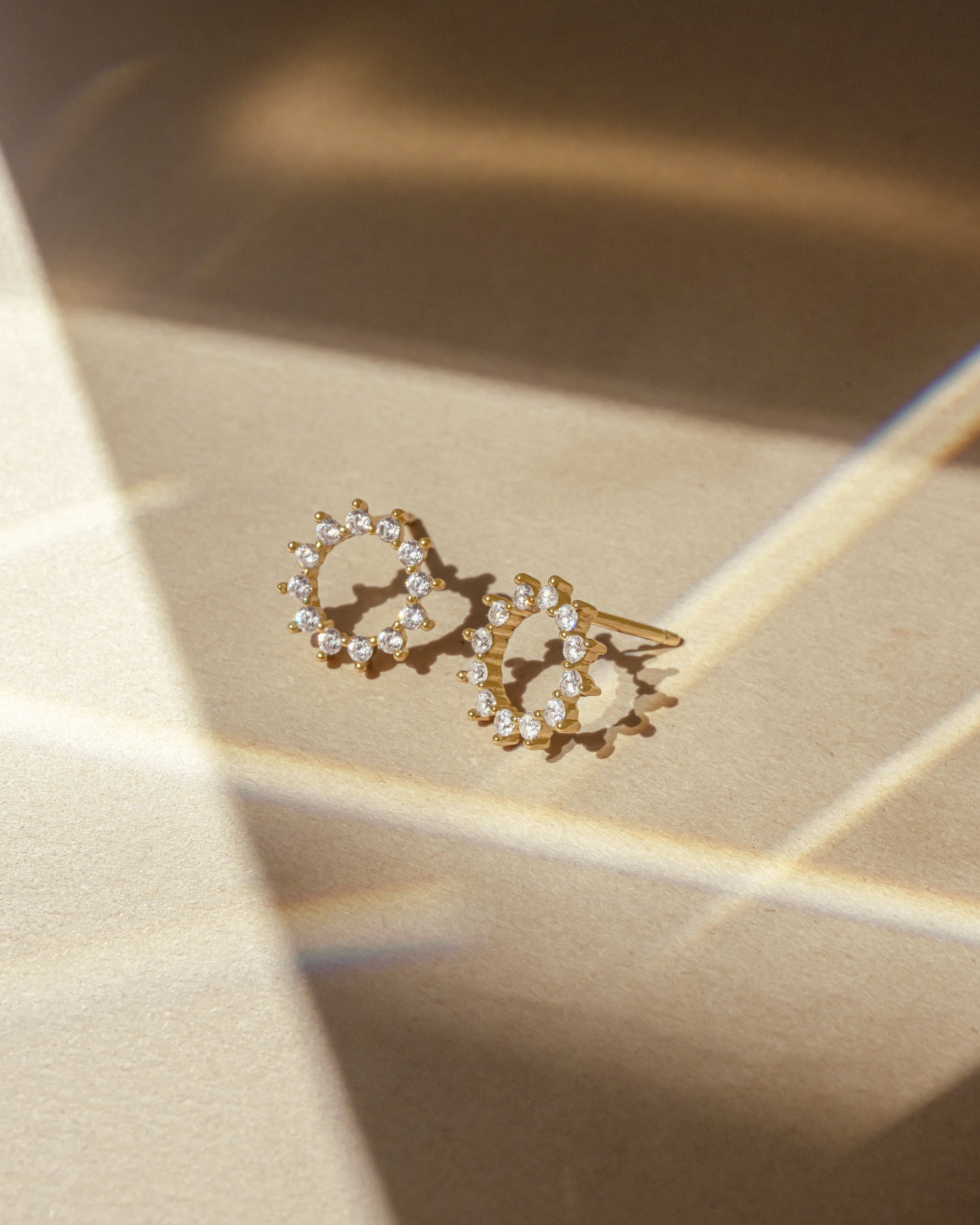 Pair of diamond stud earrings on a gold surface