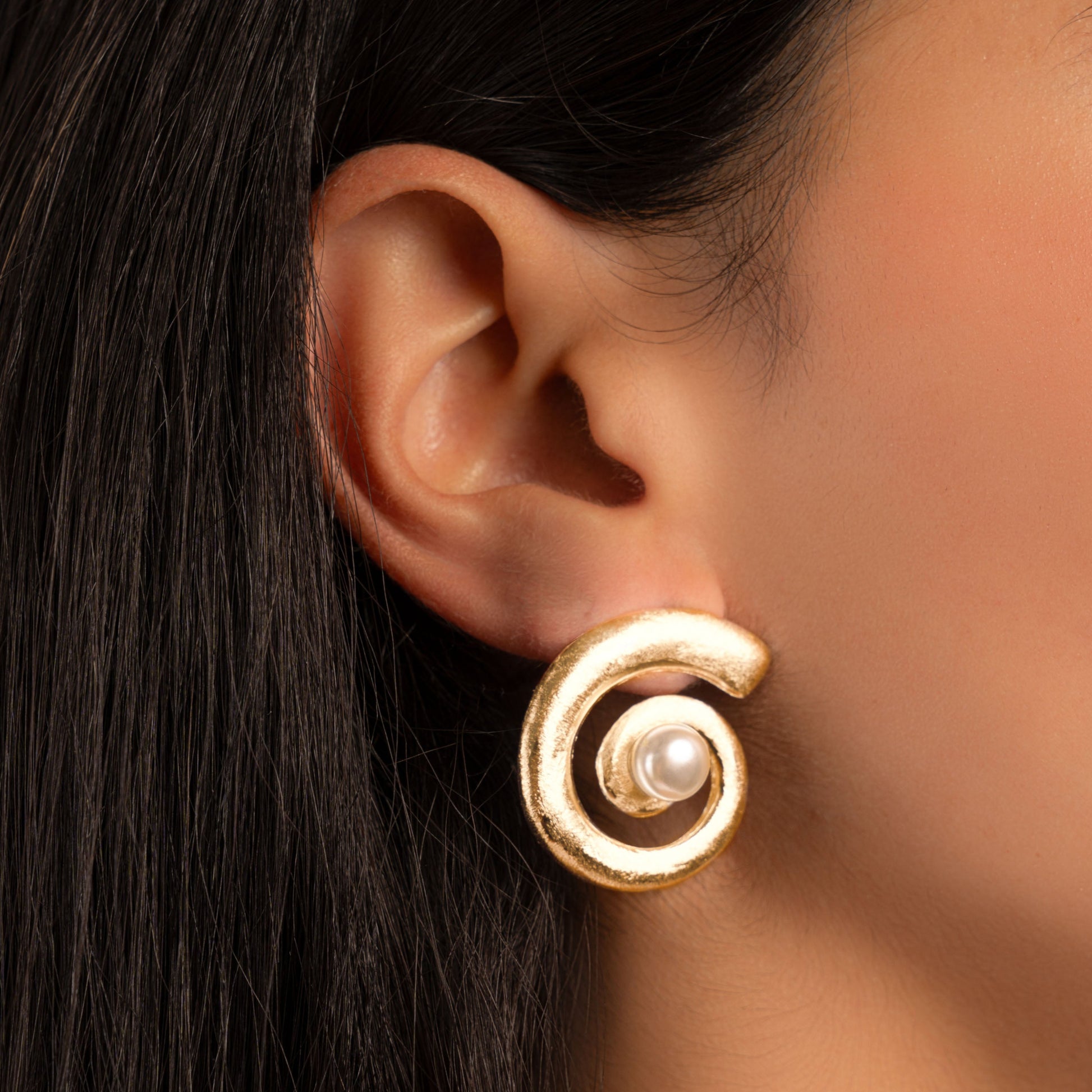 model wearing pearl earrings featuring a swirl earring design