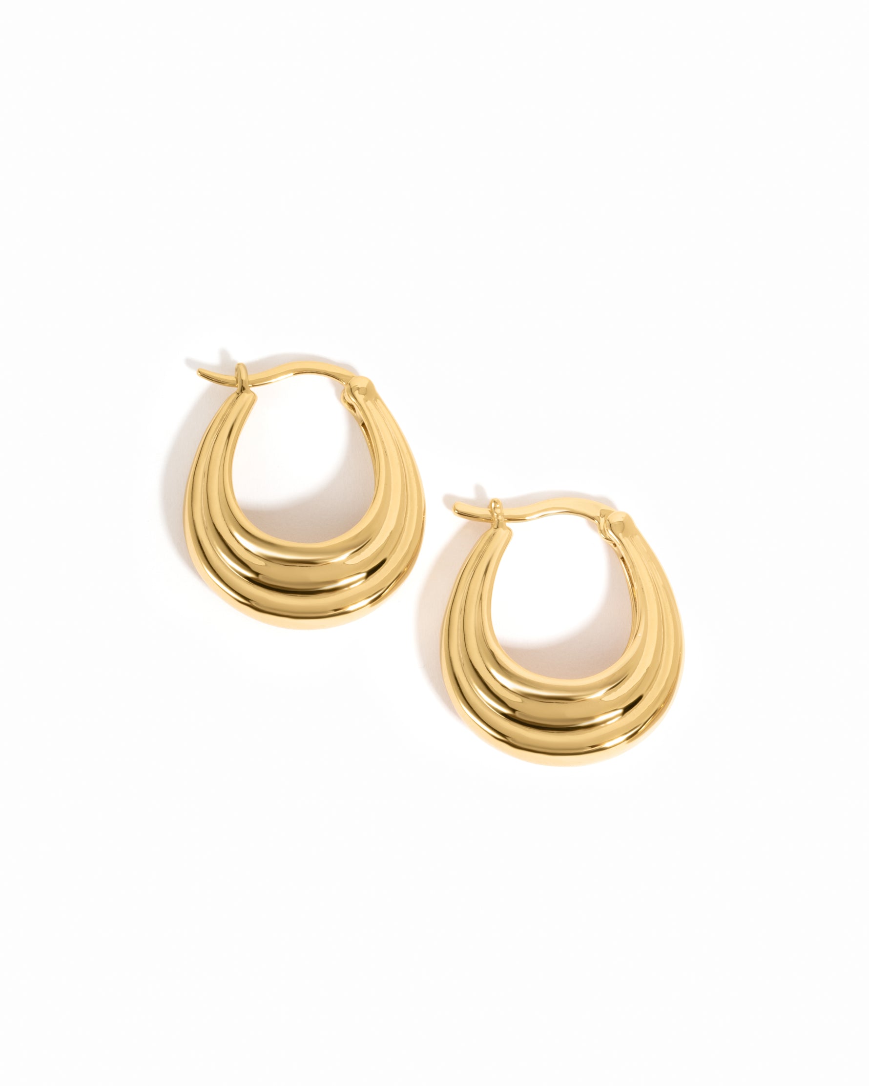 Gold thick hoop earrings on a white background