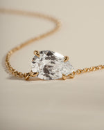 Closeup image of gold bridal jewelry featuring a teardrop necklace with a diamond pendant