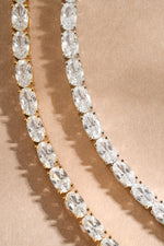 Gold diamond bracelets laying on a neutral background, one sterling silver bracelet, and one gold plated bracelet