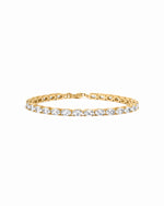 Gold tennis bracelet with oval diamond cubic zirconia stones on a white background