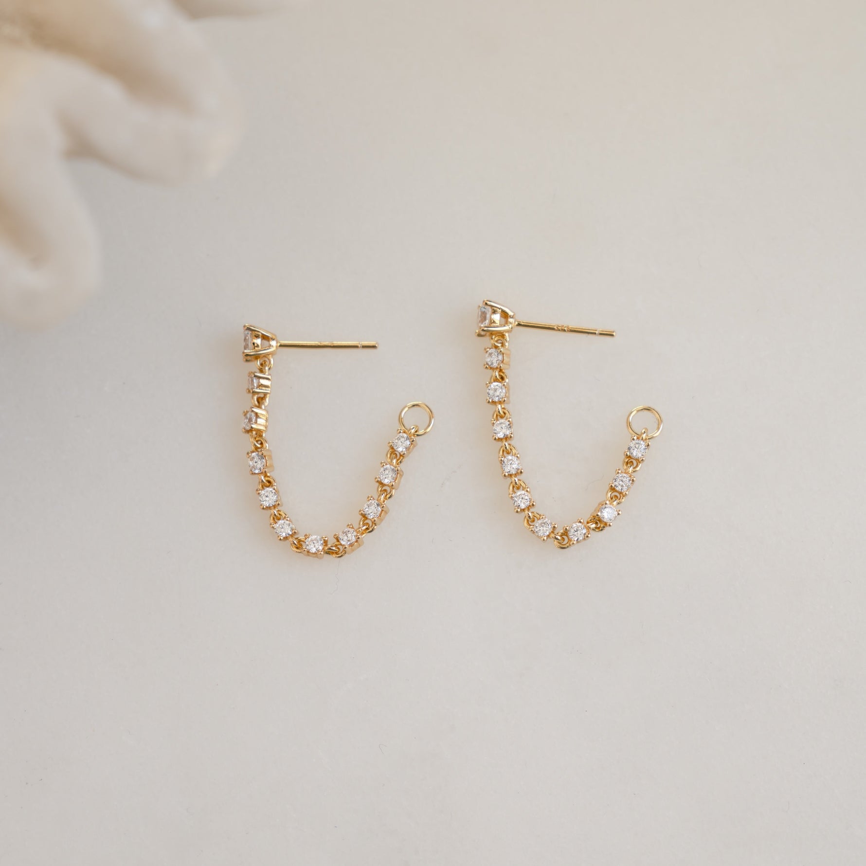 close up of gold chain stud earrings with tennis link design, perfect for a layered jewelry look.