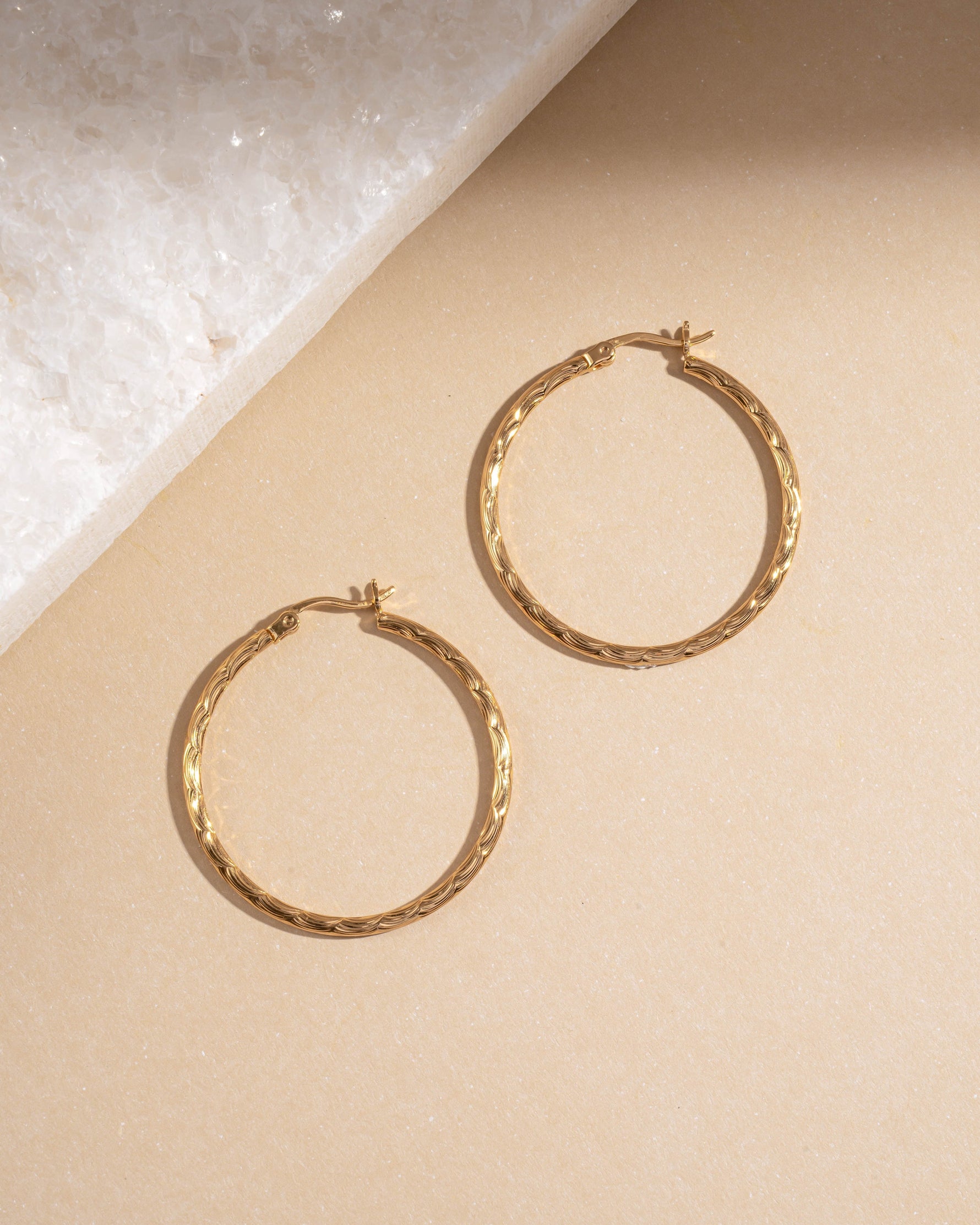Flatlay of 35mm gold textured hoop earrings with hammered twisted finish, lightweight vintage-inspired hoops for daily wear.