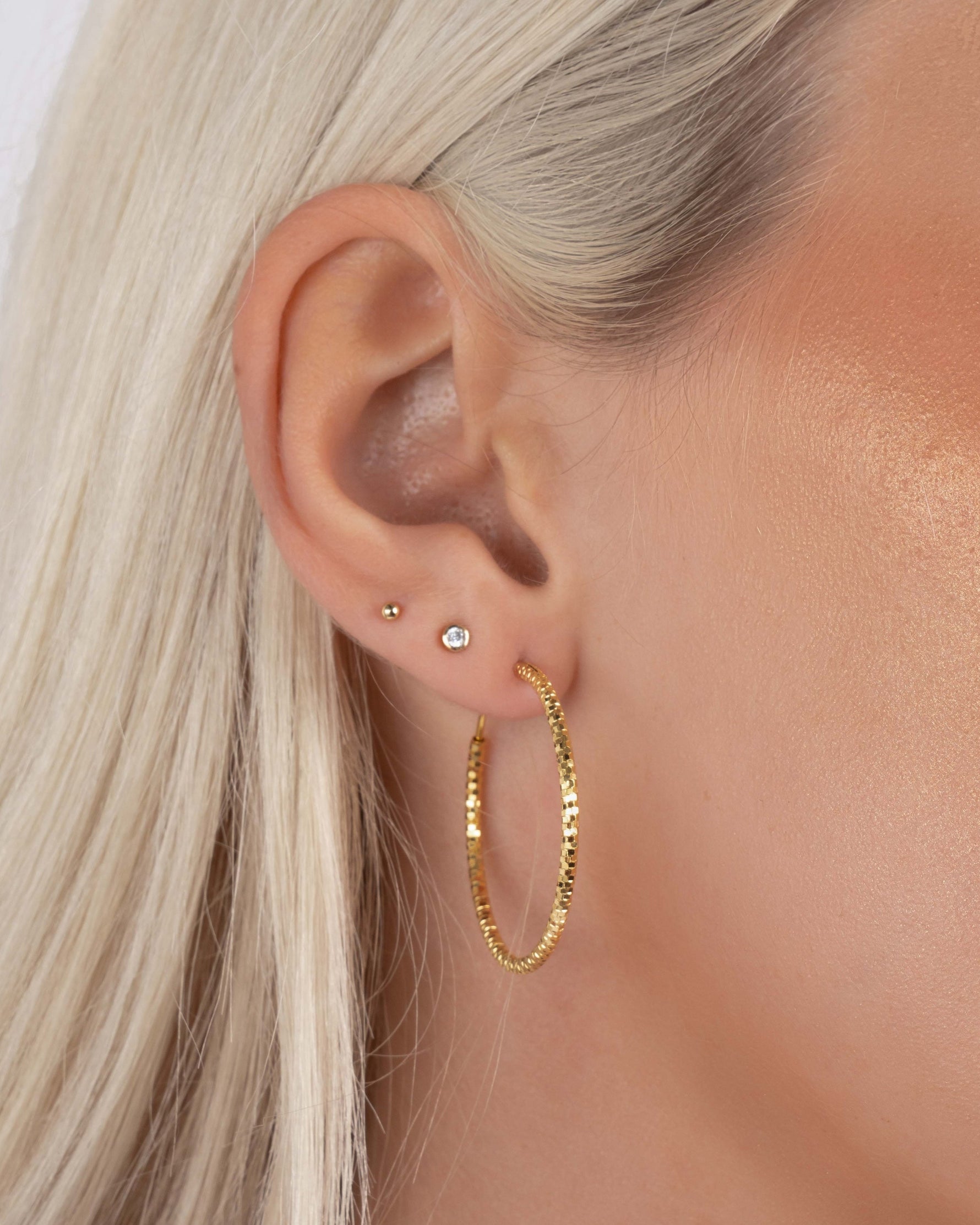 Model wearing 32mm gold lightweight  earrings, styled with bezel and ball stud earrings in second and third piercings.