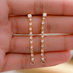 Model holding gold chain earrings in her palm, showing its dangle earring charm.