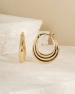 Pair of vintage earrings featuring gold hoop earrings on a textured beige surface