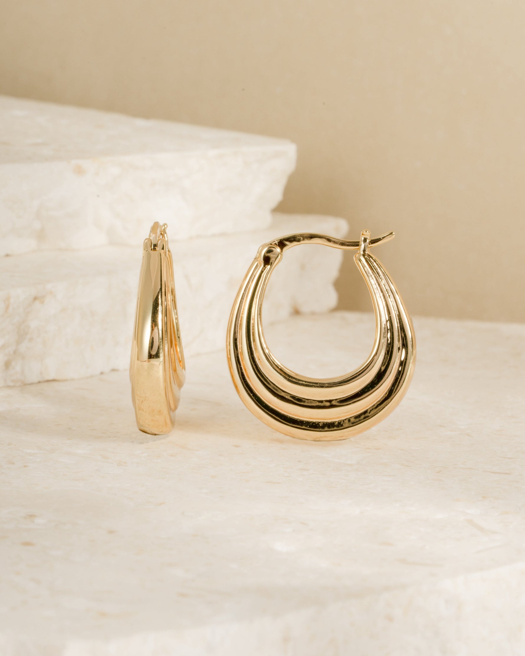 Pair of vintage earrings featuring gold hoop earrings on a textured beige surface