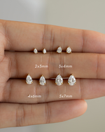 Teardrop-shaped tiny studs of different sizes displayed on a hand.