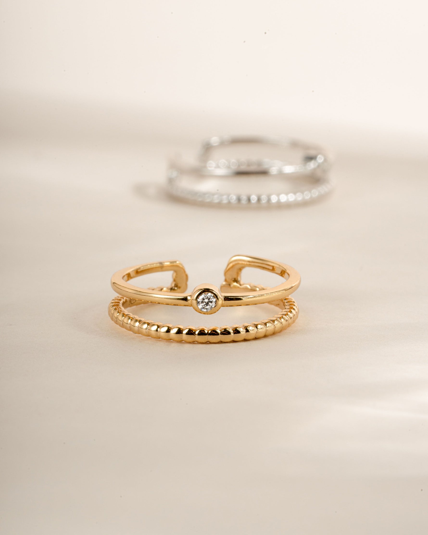 Gold foot jewelry featuring a minimalist toe ring and a silver toe ring blurred in the background