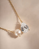 Necklace with teardrop-shaped diamond and pearl on a beige background