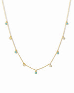 Gold necklace with small turquoise and cubic zirconia gemstones on a white background