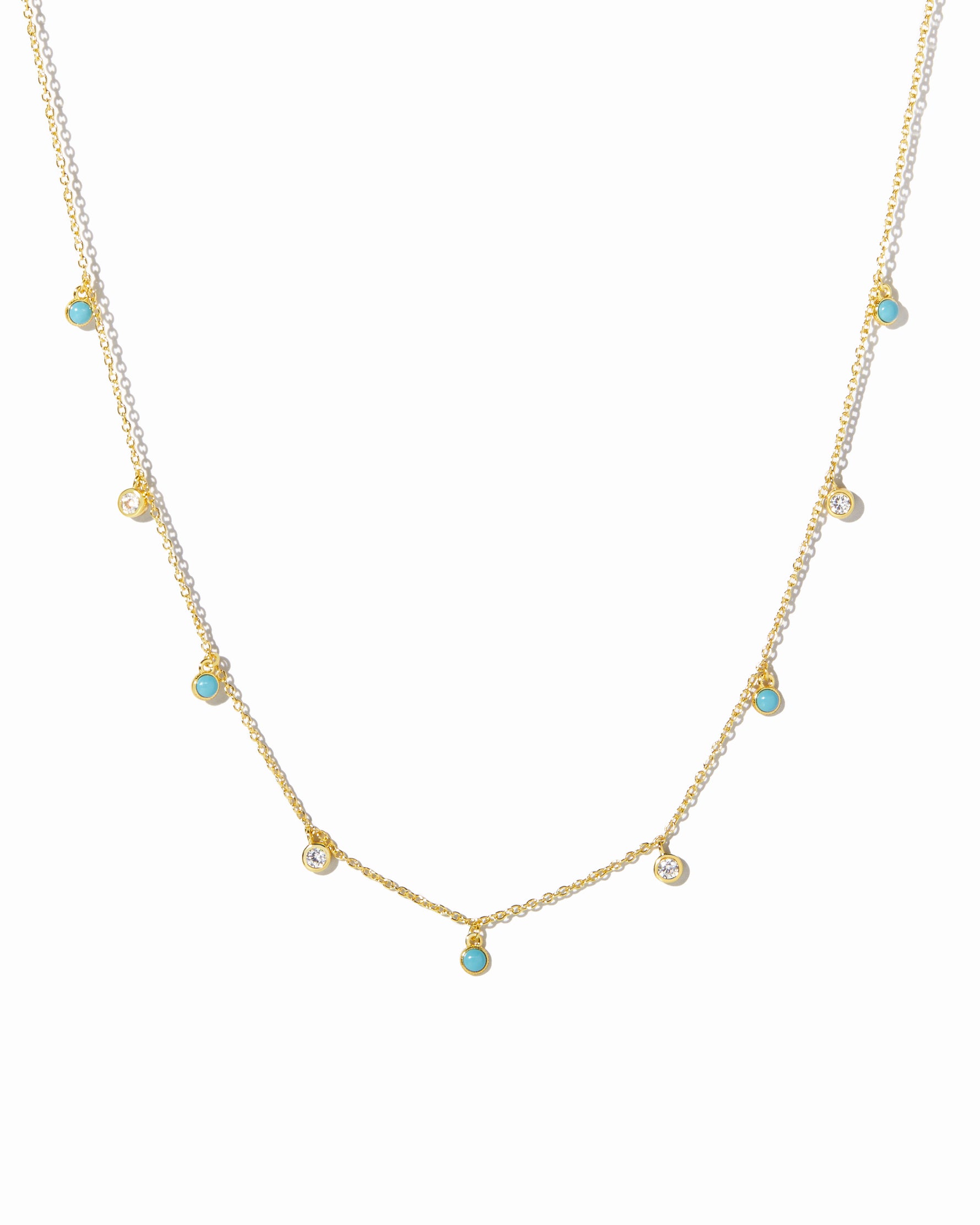 Gold necklace with small turquoise and cubic zirconia gemstones on a white background