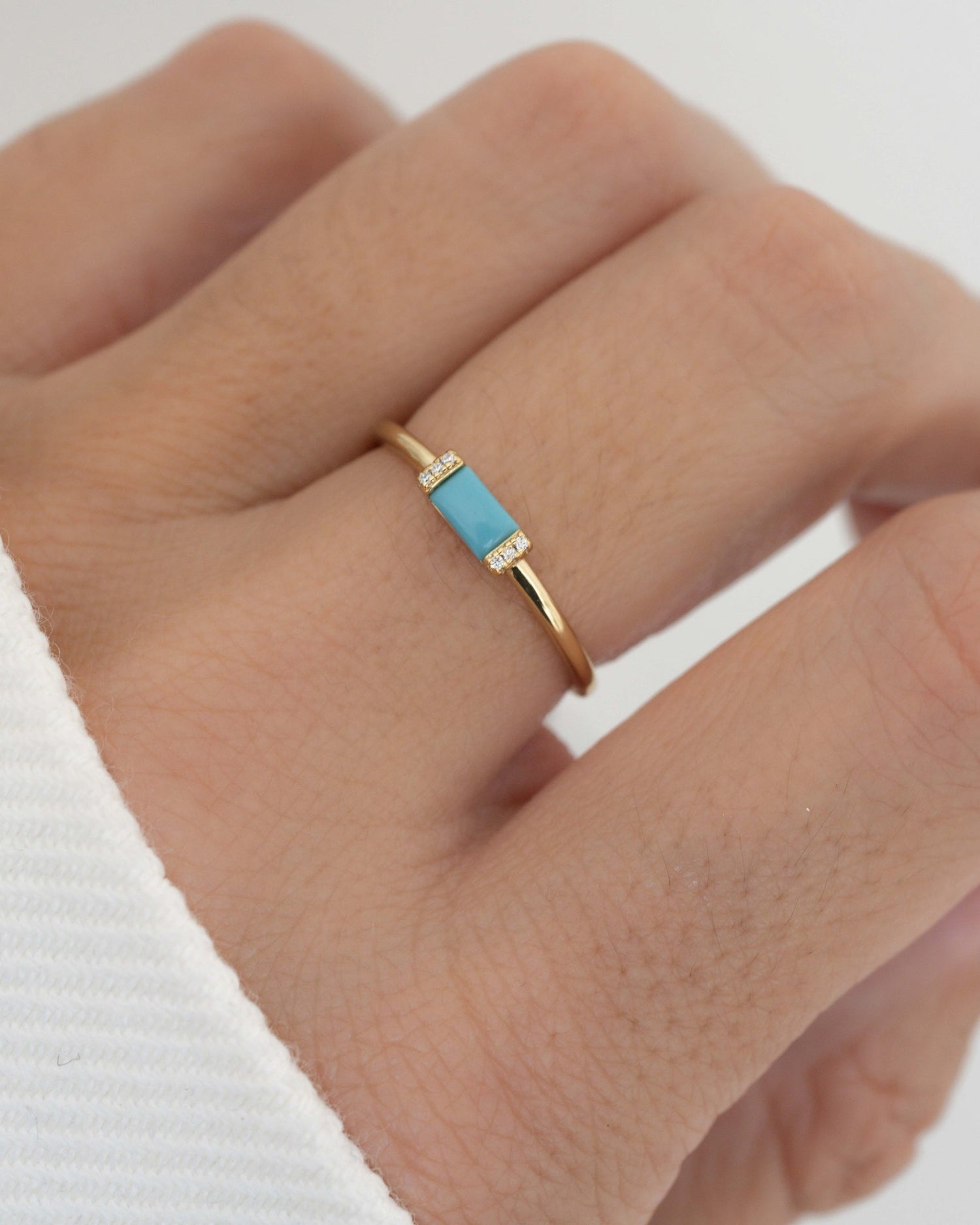 closeup image of model showcasing turquoise jewelry featuring a baguette ring with a turquoise gemstone and pave diamonds