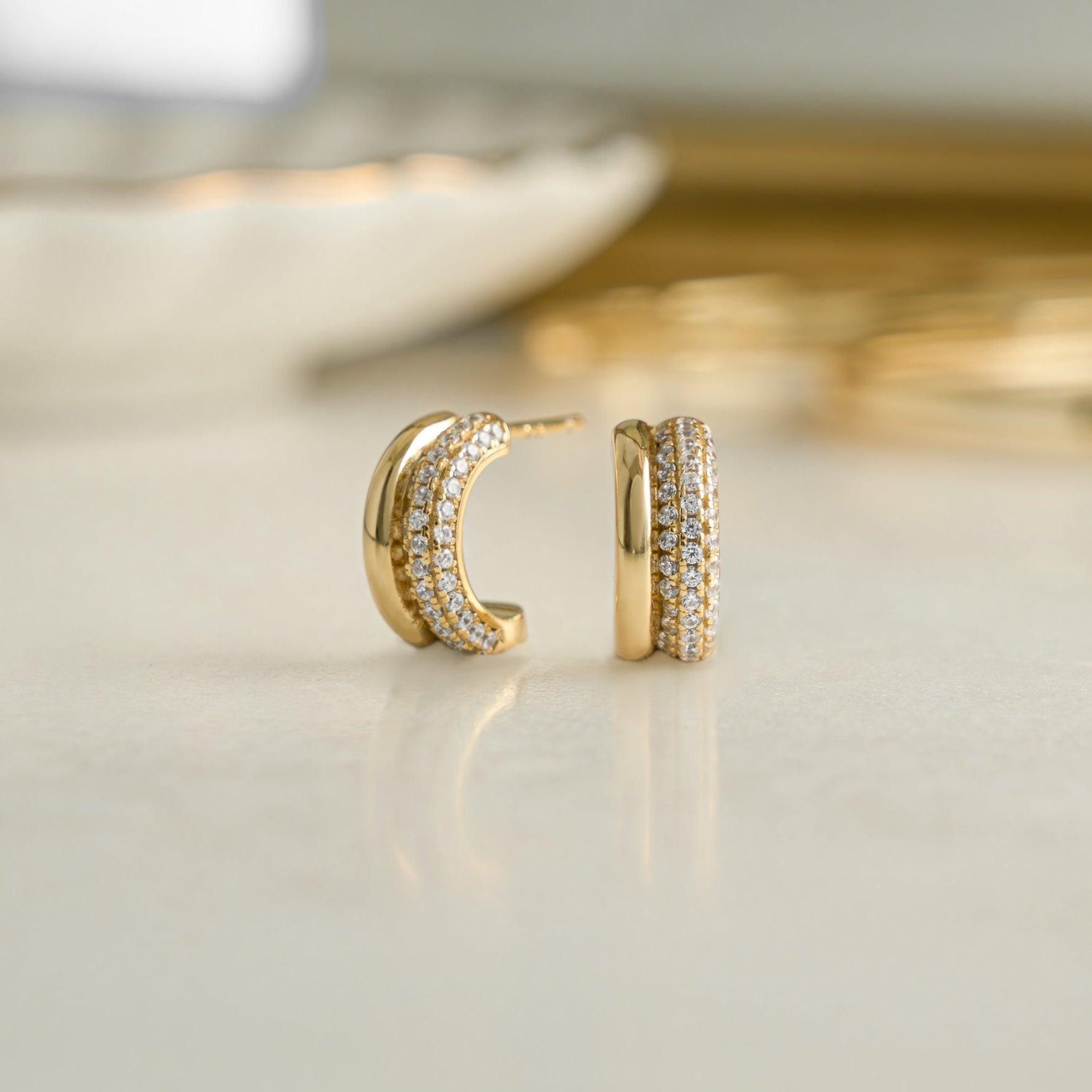 closeup image of dainty earrings featuring cubic zirconia stones wrapped on huggie earrings