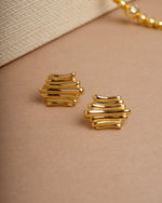 Gold vintage earrings on a beige background