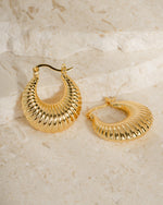 Gold statement earrings on a neutral background