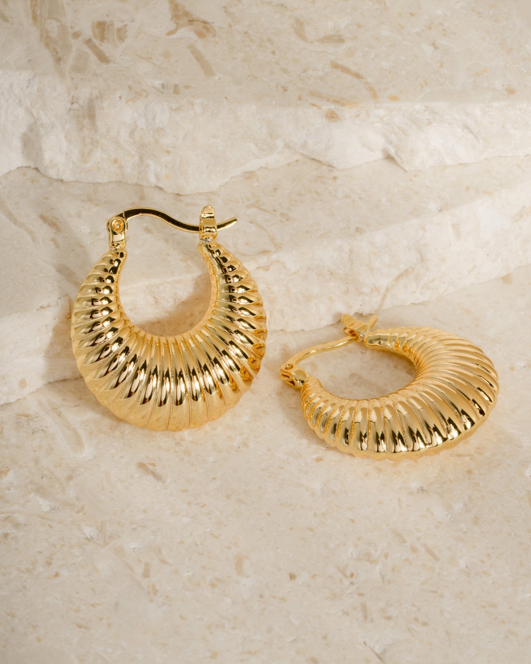 Gold statement earrings on a neutral background
