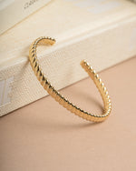 Gold spiral vintage bangle bracelet lying against decorative books