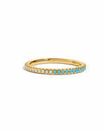 Gold ring with half white cubic zirconia half turquoise stones on a white background