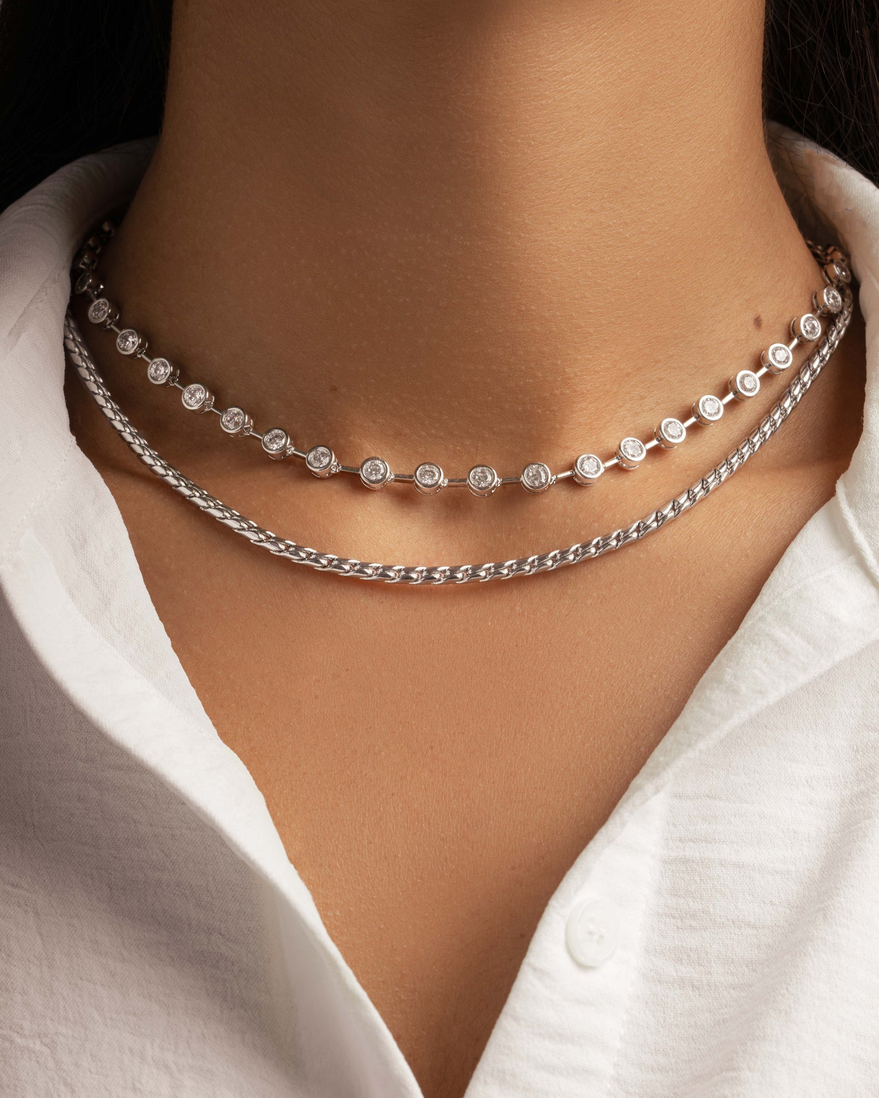 Model wearing silver stacking necklaces featuring a vintage tennis necklace and a silver chain
