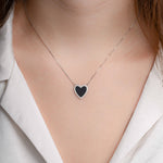 silver necklace with a black heart pendant, styled with a V-neck blouse for a sophisticated touch.
