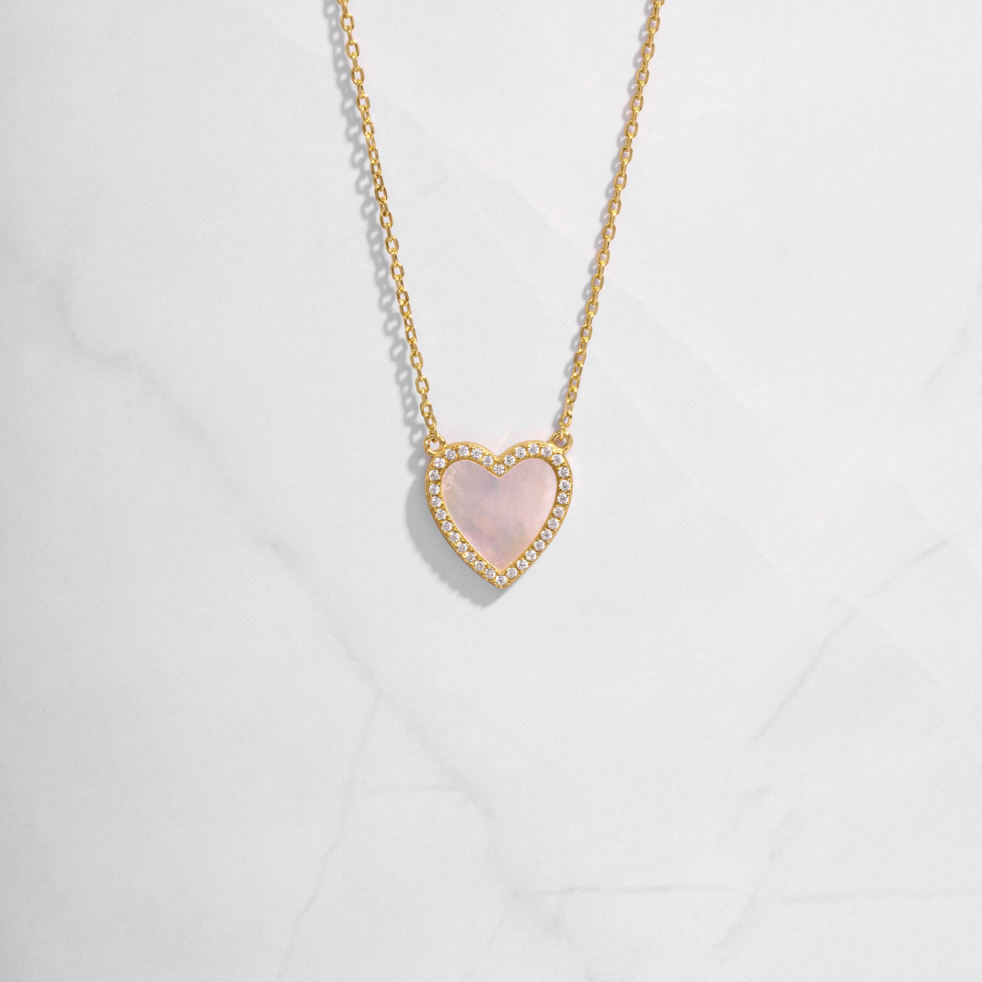 Close-up of a Mother of Pearl Heart Necklace with a smooth, luminous heart pendant on a delicate gold chain.