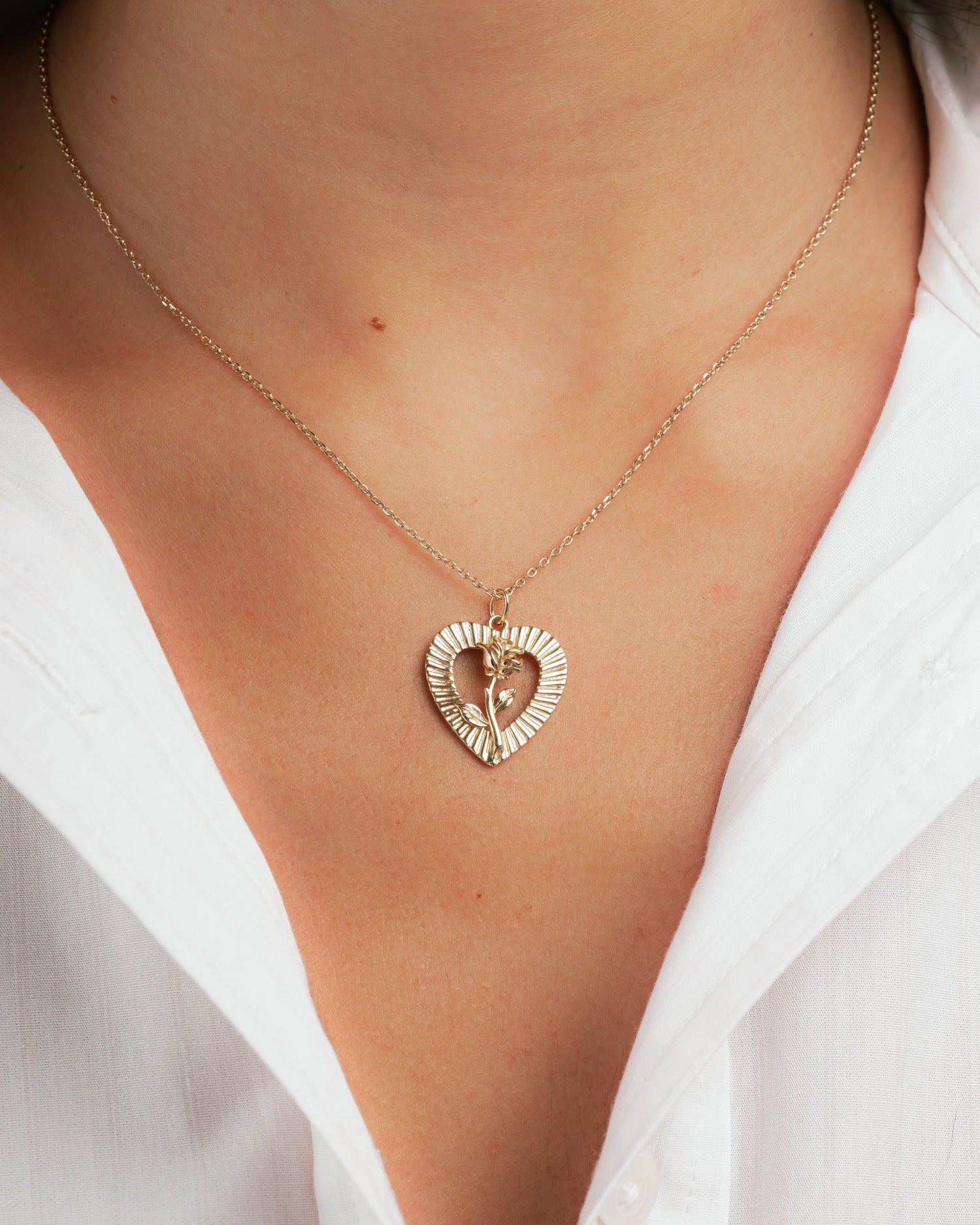 Gold heart necklace with rose pendant design on model