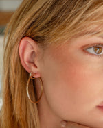 Model wearing vintage earrings featuring a gold hoop, and a dainty huggie hoop earring 