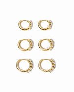 Set of gold hoop earrings with small diamonds on a white background