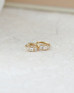 closeup image of three stone baguette cut small hoop earrings in 14k gold plating