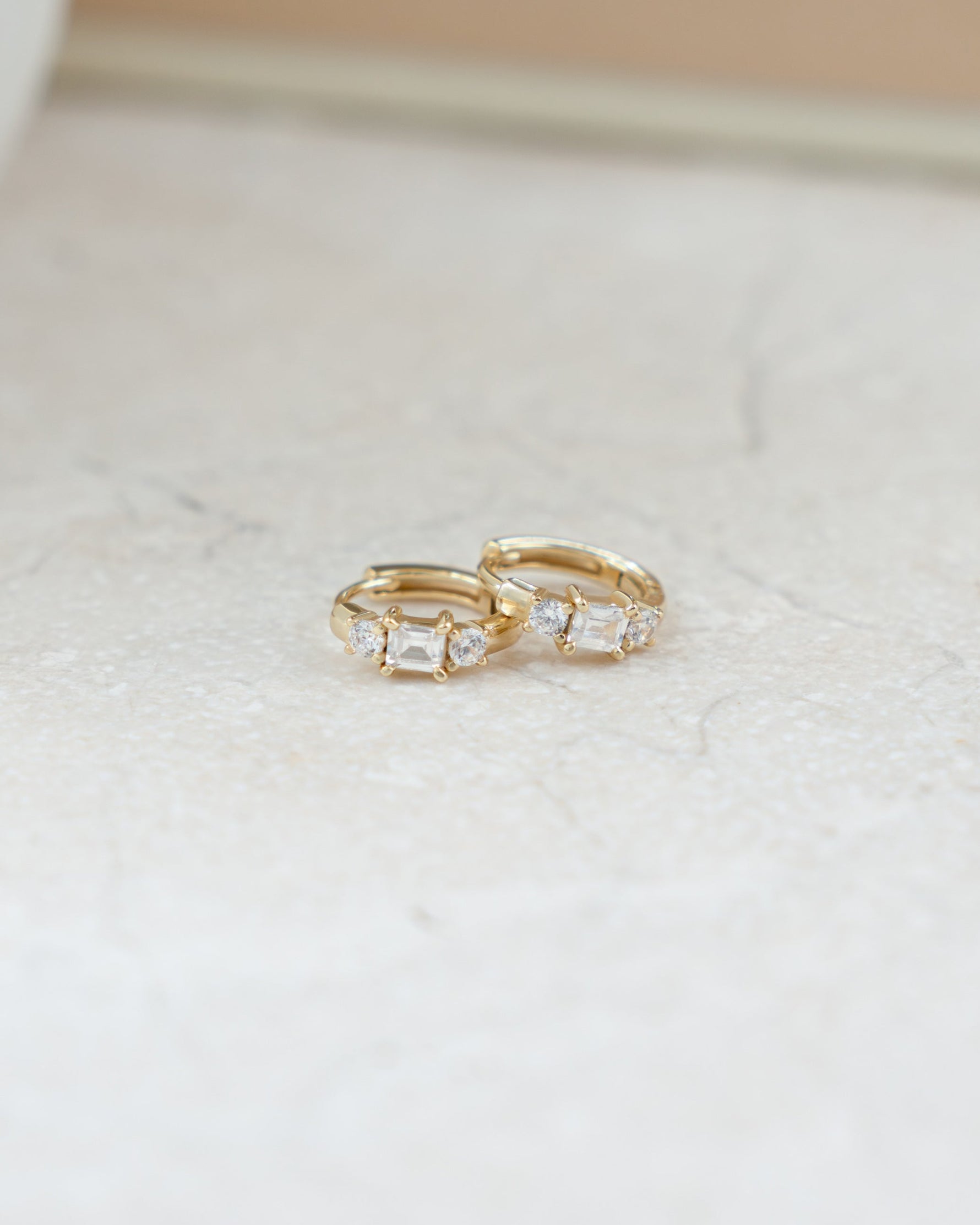 closeup image of three stone baguette cut small hoop earrings in 14k gold plating