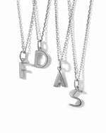 silver custom jewelry featuring different silver initial necklaces on a white background