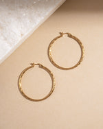 Simple earrings featuring gold hoop earrings on a beige surface