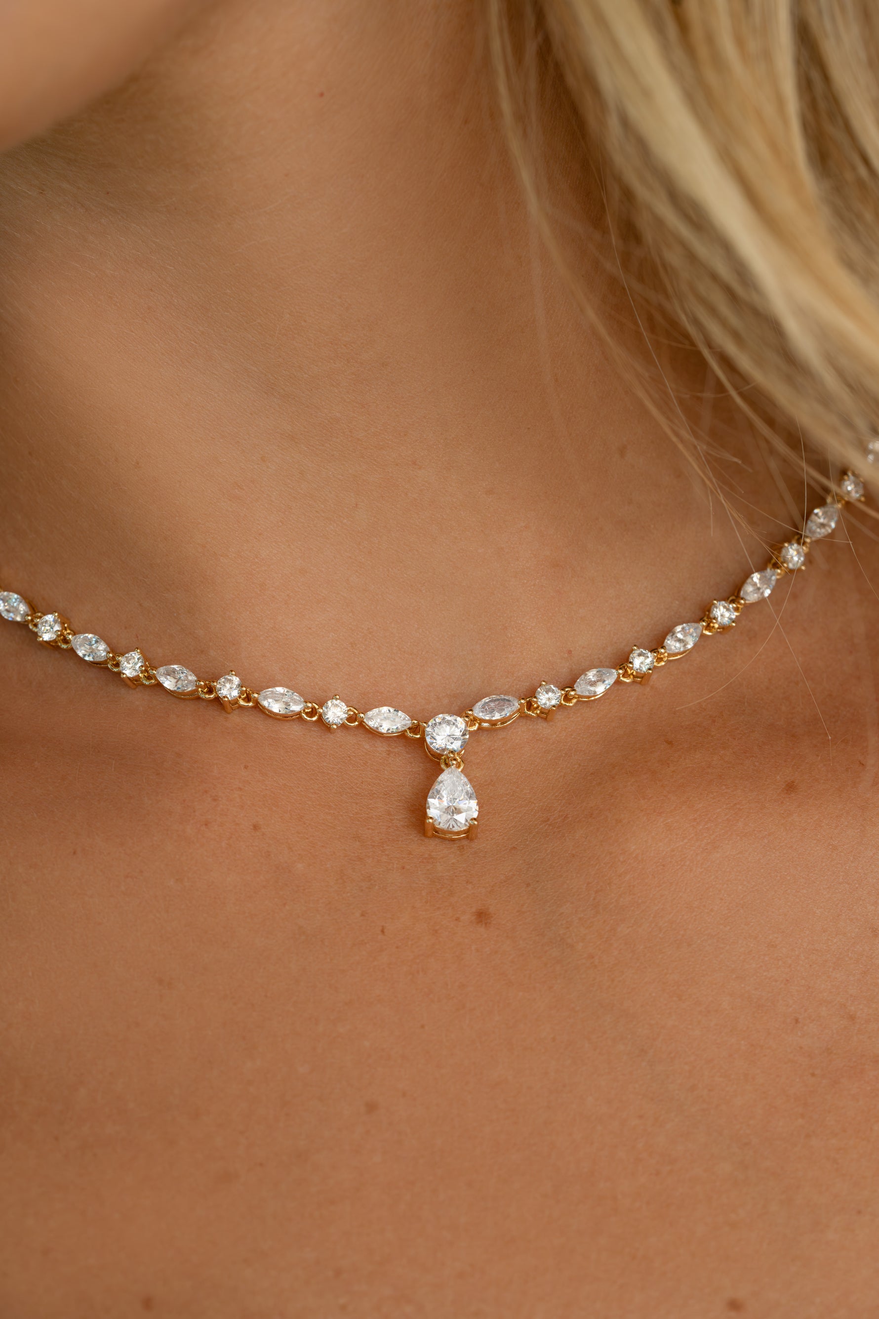 Closeup image of model wearing teardrop shaped tennis necklace with marquise cut and round stones