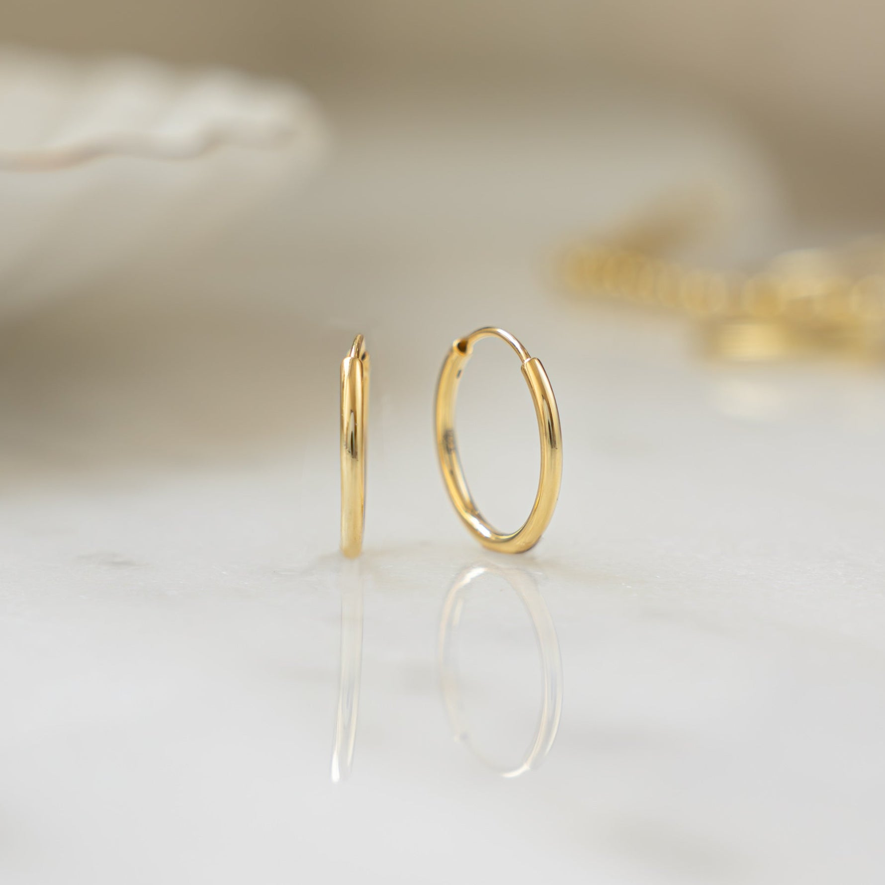 Closeup image of thin gold huggie hoops