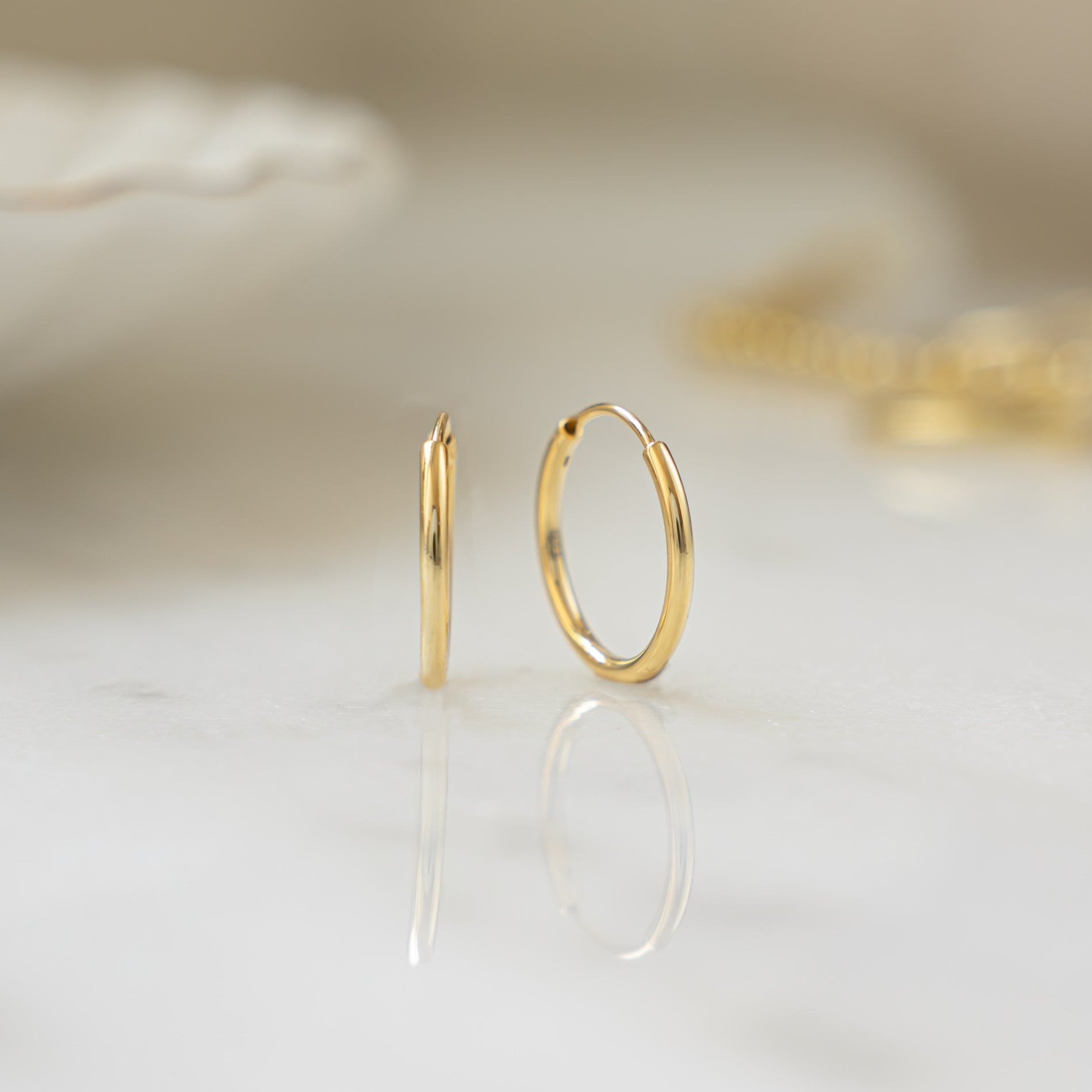 Closeup image of thin gold huggie hoops