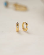 a pair of dainty gold hoop earrings with a mall cubic zirconia diamond 