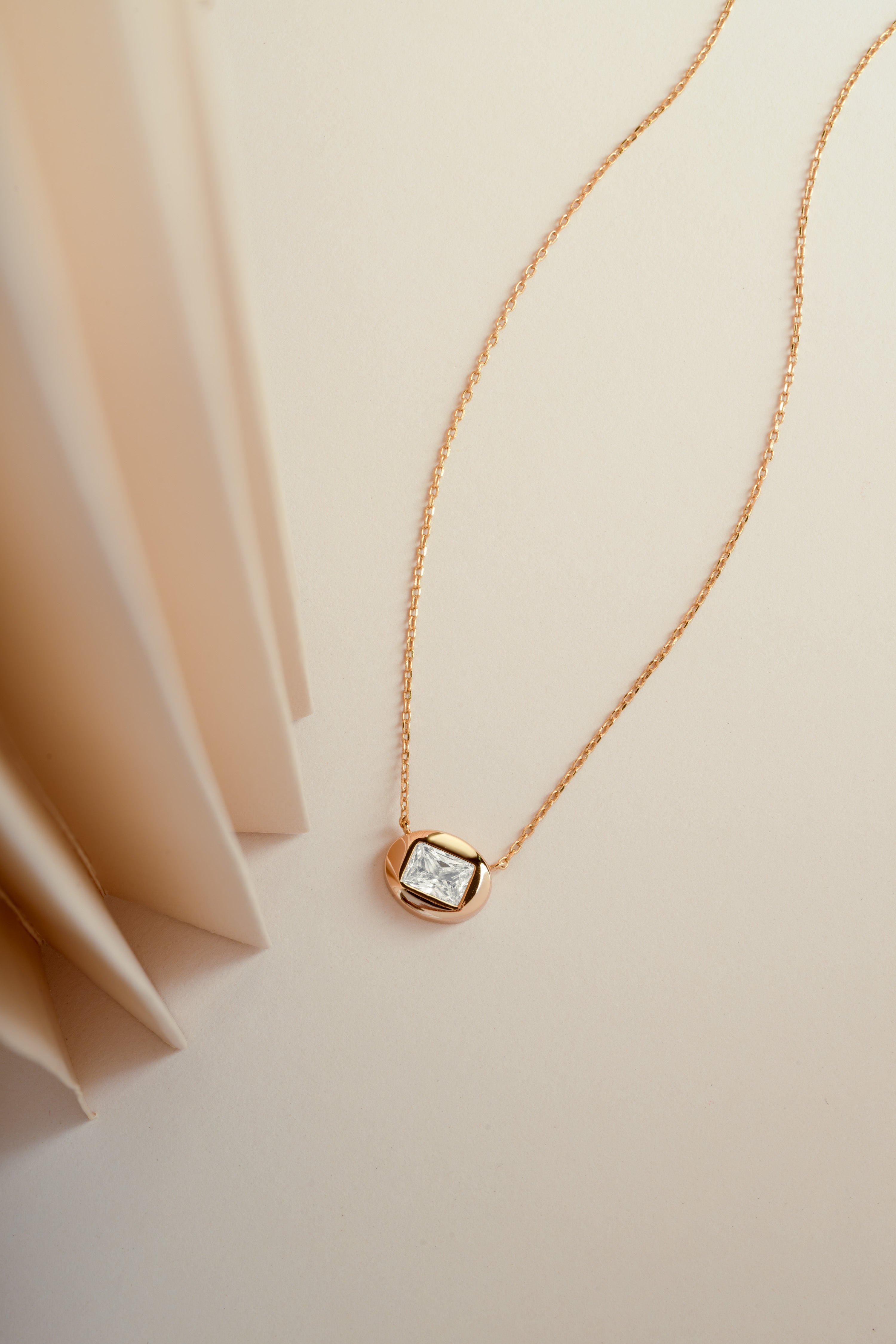 Gold chain dainty diamond necklace on a beige background