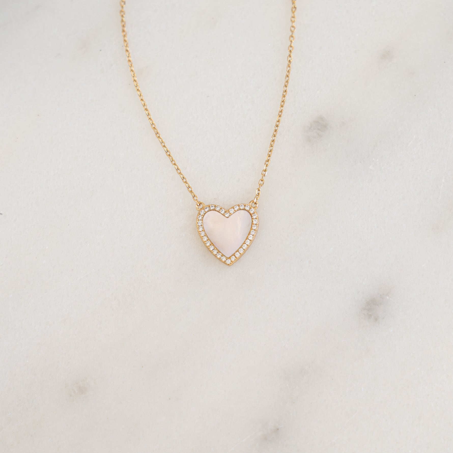 A detailed close-up of the gold diamond necklace, laid flat, highlighting the mother of pearl’s intricate details.
