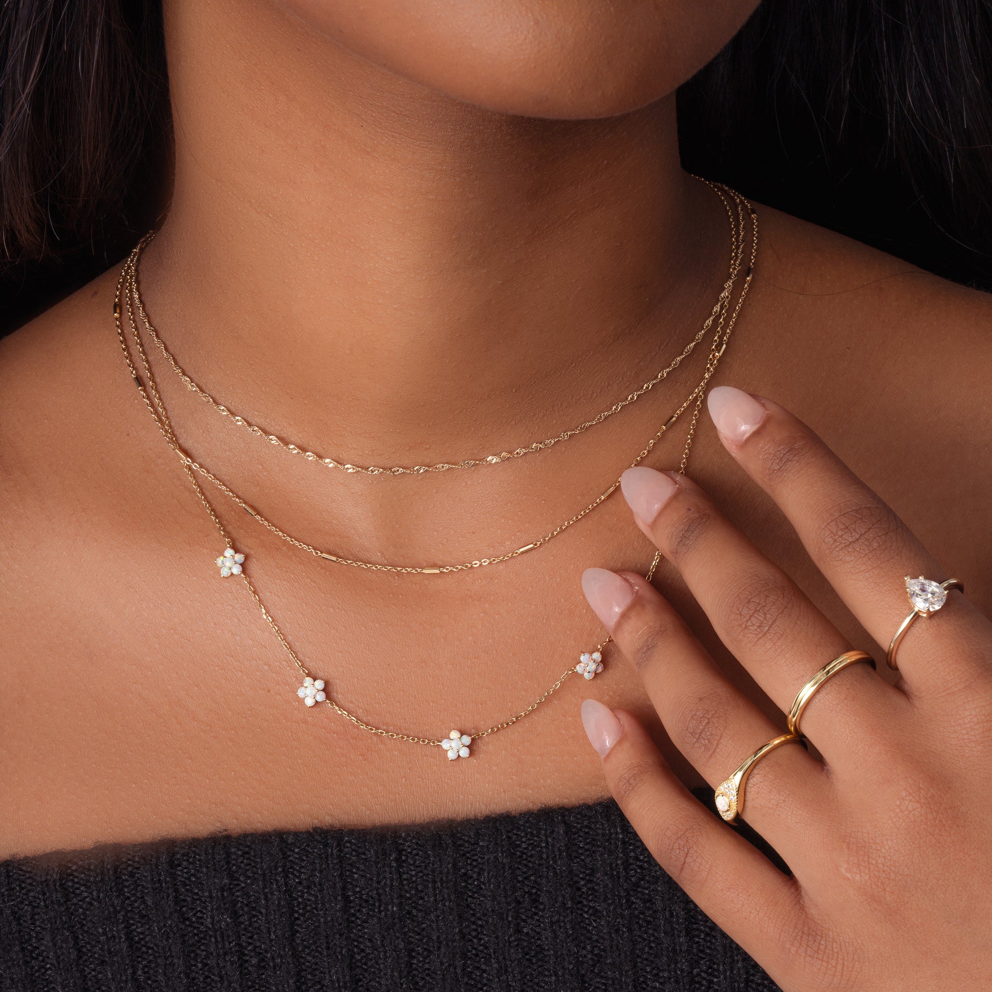 Model wearing layered gold opal necklace with other minimalist gold jewelry