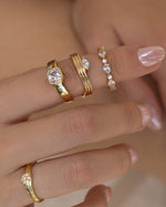 Closeup hand of gold diamond stackable rings featuring a dome ring, a marquise diamond ring, a pear stacking ring, and a vintage ring